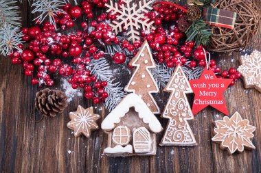 Yılbaşı süslemeleri. Noel meyveleri, ev şeklinde zencefilli kurabiyeler ve ahşap zemin üzerinde Noel ağaçları..