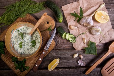 Dip sauce appetizer tzatziki of cucumber, yogurt, garlic, lemon and dill. Creece cuisine. Old wooden rustic background. Overhead. Top view.