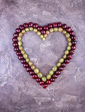 Gri beton arka planda kalp şeklinde taze kirazlar. Üst Manzara. Boşluğu kopyala.