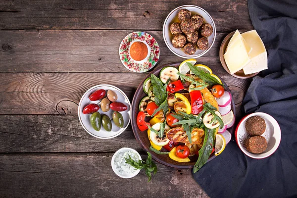 Peynir ve abur cubur seti. Eski ahşap arka planda ızgara halloumi, belper knolle, zeytin, tzatziki sosu. Masraflar. Boşluğu kopyala.