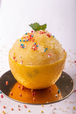 Paskalya aromalı limon meyveli şerbet. Yaz ferahlatıcı tatlıyı yarım limon kabuğuyla altın sarısı beyaz arka planda.