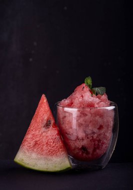 Bardakta karpuz şerbeti ve siyah zemin üzerinde taze olgun karpuz. Yaz tazeleyici tatlı. Ön manzara. Boşluğu kopyala