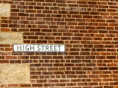 İngiltere 'nin Cotswold köyündeki eski tuğla duvarda High Street tabelası