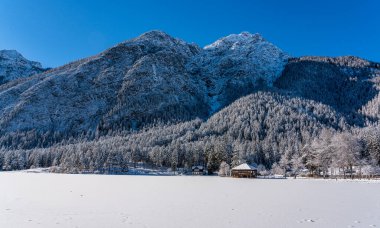 Güneşli bir kış sabahı karlı ve buzlu Dobbiaco Gölü, Bolzano ili, Trentino Alto Adige, İtalya.