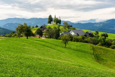 Slovenya 'daki Skofia Loka yakınlarındaki Saint Thomas Kilisesi' nin yanında İdilik yaz öğleden sonrası manzarası.