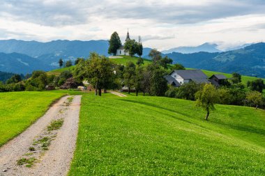 Slovenya 'daki Skofia Loka yakınlarındaki Saint Thomas Kilisesi' nin yanında İdilik yaz öğleden sonrası manzarası.