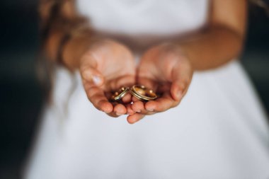 A child holds gold rings at a wedding. child's hands hold wedding rings