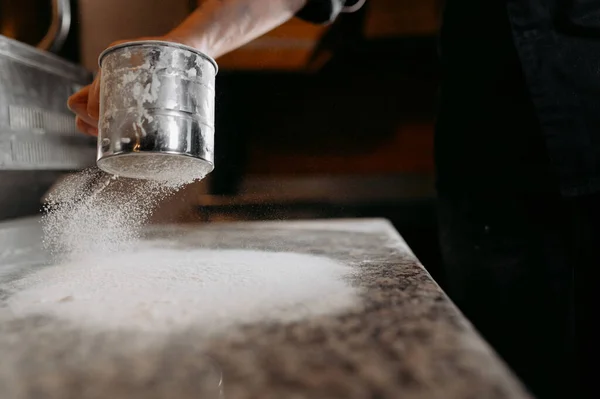 台所の少年のクローズアップは 金属のふるいを通して小麦粉を注ぎ 播種します ホームベーキングコンセプト ピザを作るプロセス — ストック写真