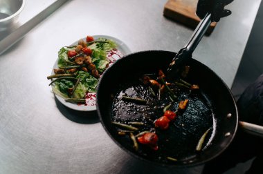 the cooked vegetables in the pan are placed on a plate. Salad preparation process. warm salad