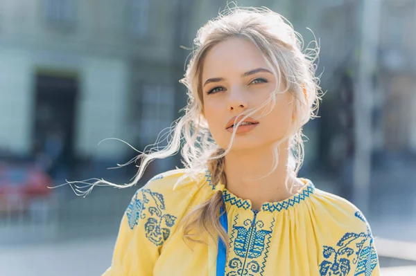 A young girl stands in a Ukrainian national ethnic embroidered dress on a sunny day.