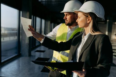 Bir iş kadını ve bir mimar ofis içi bir projeden bahsediyorlar.