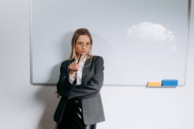 Genç öğretmen modern sınıfta beyaz tahtanın yanında..