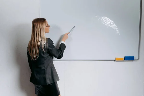 stock image young teacher writes on the board, explains exercises to students studying, holding a pen