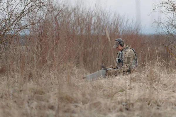 Ordu mensubu kamuflajlı bir şekilde dizüstü bilgisayarla çalışıyor..