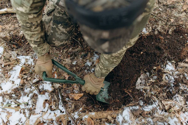 stock image a soldier with a shovel in his hand digs the ground.