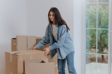Bir kadın yeni bir daireye taşınmak için eşyalarını kutulara koyar. bir eve taşınmak.
