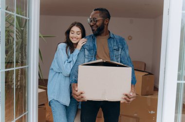 Mutlu genç adam heyecanlı karısına sarılıyor taşınma gününü karton kutularla, kiracılarla kutluyor.