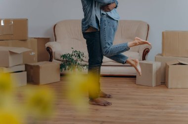 Kot pantolonlu genç bir adam, karton kutularla çevrili bir eş, mutlu Afro-Amerikan çifti eğleniyor.