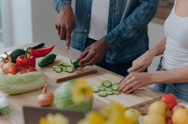 Mutfakta sebze doğrayan bir çiftin elleriyle kesme tahtasını kapat. Vejetaryen sağlıklı yiyecekler