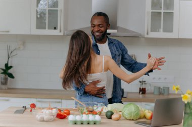 Birlikte yemek pişirirken mutfakta dans eden mutlu ve romantik bir çift. Afro-Amerikalı kadın ve erkek mutfakta eğleniyor.