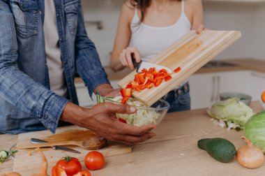 Mutfakta sebze doğrayan bir çiftin elleriyle kesme tahtasını kapat. Vejetaryen sağlıklı yiyecekler