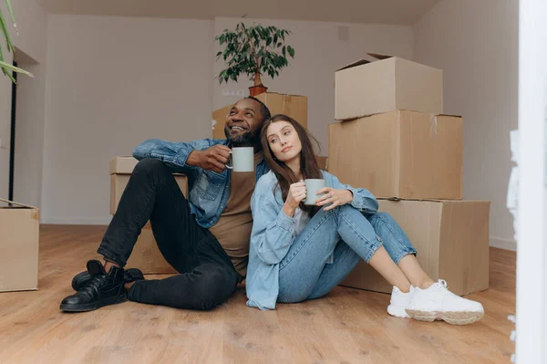Couple moving in house. interracial couple sitting near cardboard boxes