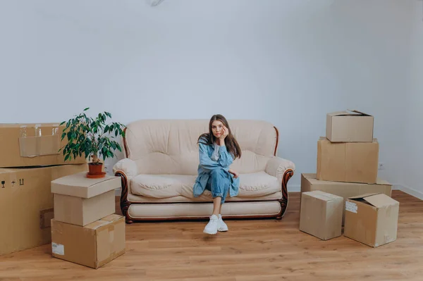 Woman packing to move in a new apartment. a woman sits on a sofa near boxes