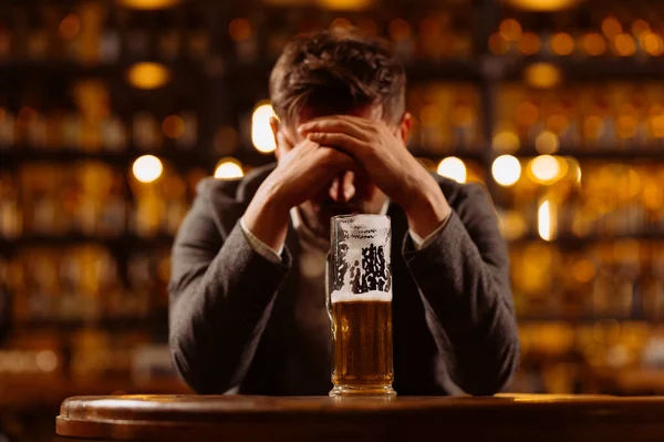 Smutny Młodzieniec Garniturze Patrzący Szklankę Piwa Siedząc Przy Stole Pubie — Zdjęcie stockowe