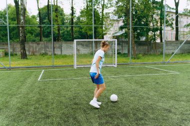 Kız futbolcu futbol sahasında topla birlikte çalışıyor. Antrenmanda futbolcu