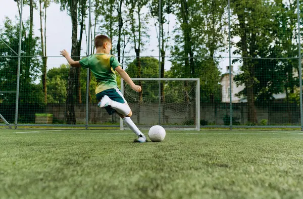 Küçük bir futbolcu kalede topa vuruyor. Çocuk Futbol Oynuyor