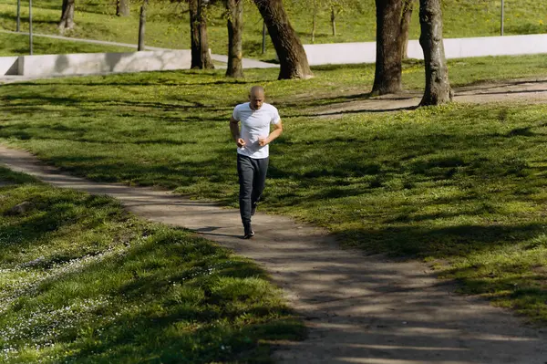 bald man runs in the park. morning run. running in nature