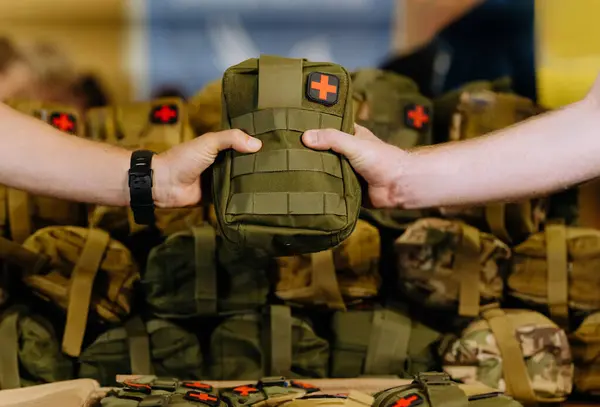 Kamuflajlı askeri ilk yardım çantası. El ele tutuşup, askeri ilk yardım çantasını teslim ediyorlar..