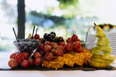 Kutlama masası için tabakta meyve tabağı. Böğürtlen ve doğranmış meyve lezzetli ve sağlıklı bir vejetaryen tatlısıdır. Yemek servisi..