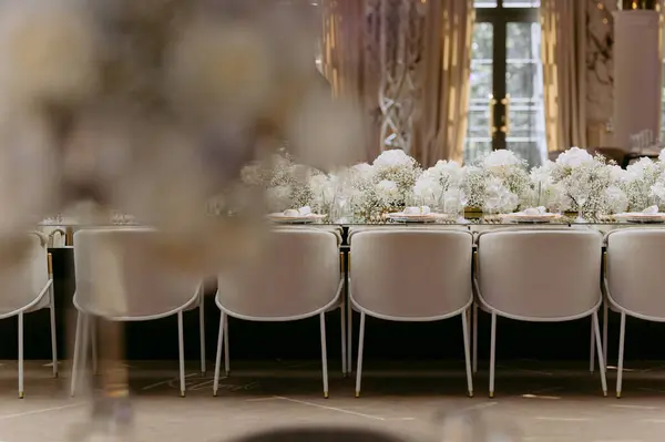 Bir buket çiçekli lüks masa. Sandalyelerle süslenmiş şenlik masası. Düğün, doğum günü ve vaftiz için ziyafet masası.