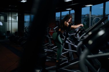Genç profesyonel antrenör kadın bir fitness stüdyosunda stepper simülatörüyle meşgul. Spor sınıfındaki güzel kız. Akşam sporu. Spor ve sağlık. Etkin yaşam biçimi