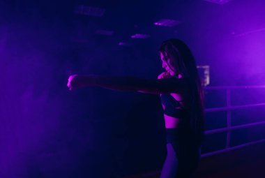 Genç seksi kız boksör boks ringinde gölgeyle boks yapıyor. Boksör salonda ringde yumruk pratiği yapıyor. Kız kickboksçu, boksör