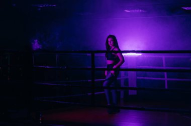 Boks ringinde genç ve seksi bir kadının portresi. Boks ringinde poz veren seksi bir kadın. Arkadan iç.