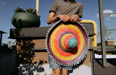 Genç bir adam Meksikalı bir sombrero tutuyor. Zenci Meksikalı şapkası bir adamın ellerinde