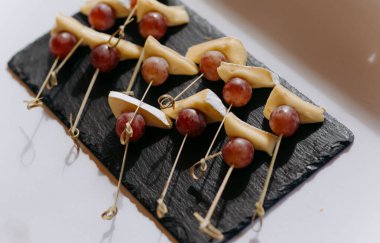 Tahtaya yerleştirilmiş peynir ve üzümlü lezzetli atıştırmalıklar. Şiş aperatifler toplantılar için davet edici bir sunum oluşturur.