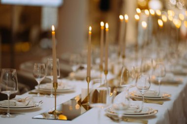 Mumlar, cam eşyalar ve yemek takımlarıyla zarif bir şekilde düzenlenmiş bir masa. Ortam sıcak ve davetkar. Resmi toplantılar ve kutlamalar için mükemmel..