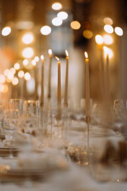 Çok güzel dizilmiş bir masa uzun boylu, yanan mumlar ve sıcak bir parıltı. Cam eşyalar ve güzel yemek parçaları toplanma için davetkar bir ortam yaratır..