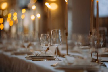 Çok güzel düzenlenmiş bir masa camdan yapılmış ve mumlar sıcak bir ortam yaratıyor. Konukların unutulmaz bir yemeğin tadını çıkarması için cilalı yemeklerle güzel bir yemek düzeni..