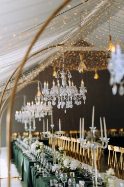 Şatafatlı avizeler ve şamdanlar güzel düzenlenmiş bir masayı süsler. Yumuşak ışık, özel bir kutlama için romantik bir ortam yaratır..