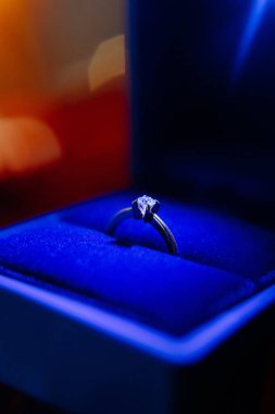 Göz kamaştırıcı bir yüzük, kadife bir kutuda ihtişam sergiliyor. Yumuşak ışıklandırma bu değerli mücevher parçasının ince detaylarını arttırır..