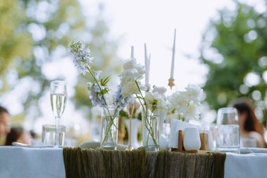 Sofistike masa düzenlemelerinde taze çiçekler ve cam eşyalar var..