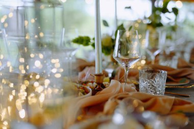 Işıl ışıl cam örtüler, yumuşak örtüler ve parıldayan ışıklar olan güzel düzenlenmiş bir masa romantik bir akşam yemeği ya da şenlikli bir toplantı için ideal..