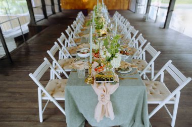 Zarif çiçek süslemeleri, gurme yemekleri ve yumuşak ışıklandırma içeren güzel düzenlenmiş bir masa. Özel durumlar ve toplantılar için mükemmel..