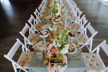 Zarif çiçekler, gurme yemekleri ve zarif sofra takımları olan, özel günler ve kutlamalar için mükemmel düzenlenmiş bir yemek masası..