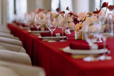 Zarif cam eşyalar, lüks peçeteler ve zarif tonlarda sersemletici çiçek süslemeleri olan güzel düzenlenmiş bir yemek masası, üst sınıf bir toplantı için mükemmel..