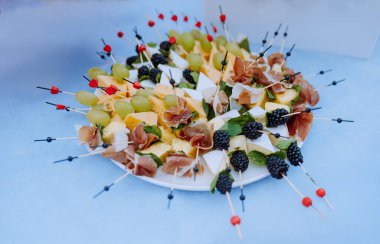 Çeşitli peynirler, taze meyveler ve dekoratif şişler ile dolu canlı bir tabak, partiler ve toplantılar için mükemmel..